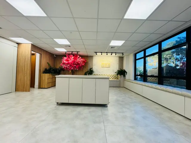 Balcão central do lounge em frente à árvore de flores rosas e ao painel Derma Club