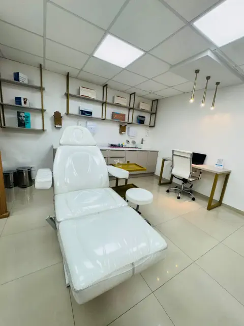 Maca elétrica branca em primeiro plano, mocho, carrinho dourado e mesa de atendimento ao fundo