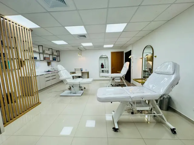 Sala de procedimentos ampla com três macas, ripado de madeira e bancada com prateleiras